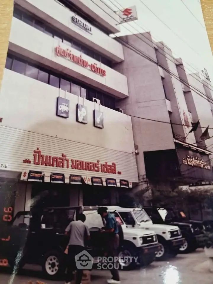Commercial building exterior with car dealership and signage in urban setting.