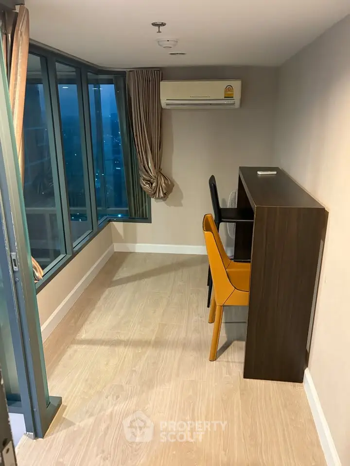 Modern study room with large windows and stylish furniture in high-rise apartment.