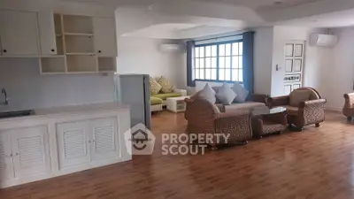 Spacious open-plan living room with elegant wicker furniture and wooden flooring.