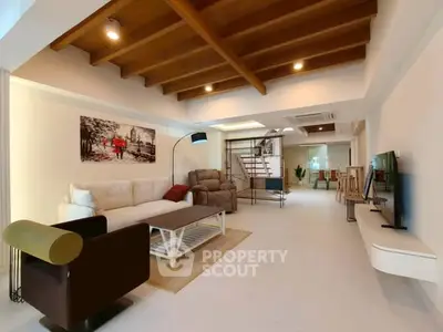 Spacious modern living room with stylish furniture and wooden ceiling beams.