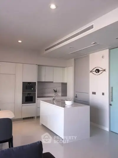 Modern kitchen with sleek white cabinetry and island, featuring built-in appliances and minimalist design.