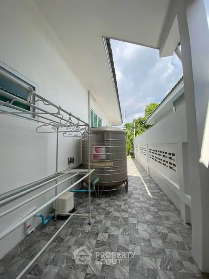 Spacious outdoor utility area with water tank and drying racks, perfect for practical home living.