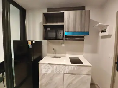 Modern compact kitchen with sleek cabinetry and built-in appliances in a stylish apartment.