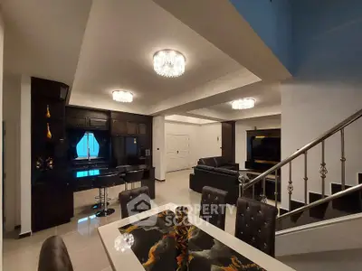 Luxurious open-plan living and dining area with modern kitchen and elegant staircase.