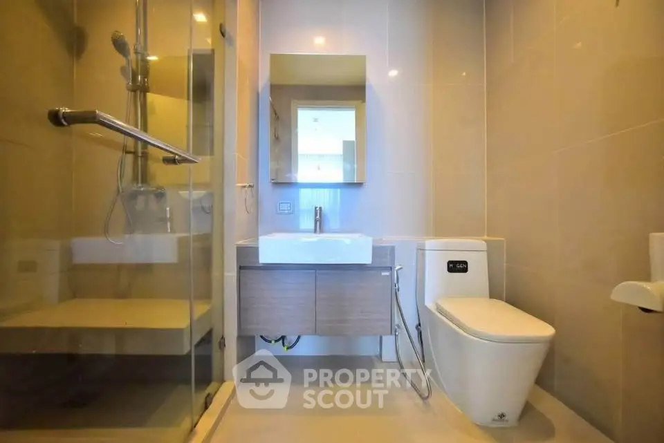 Modern bathroom with glass shower and sleek fixtures in contemporary apartment.