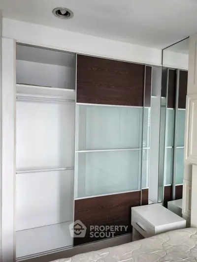 Modern bedroom with sleek built-in wardrobe and mirrored panels, maximizing space and style.