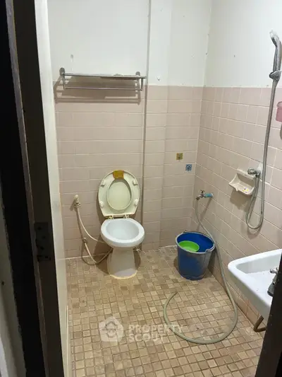 Compact bathroom with shower, toilet, and tiled walls, ideal for budget-friendly renovations.