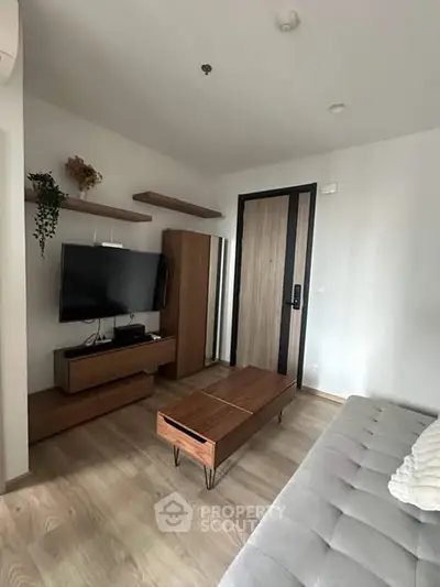 Modern living room with sleek furniture and wall-mounted TV, showcasing minimalist design and cozy ambiance.