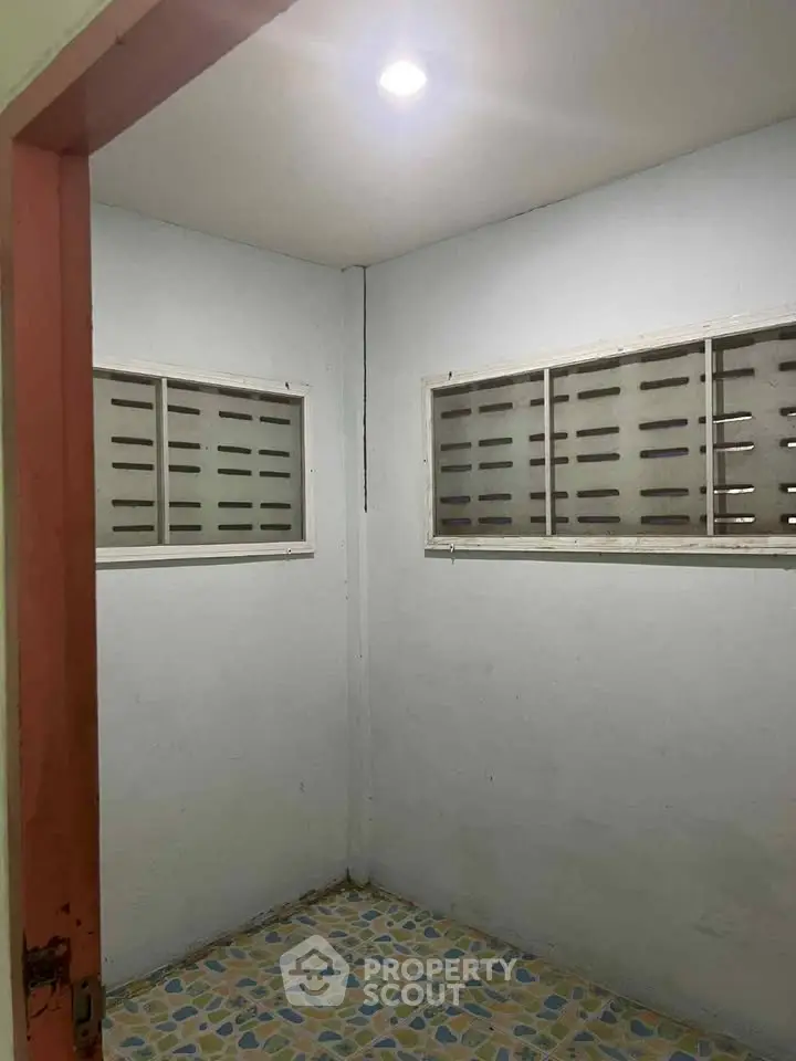 Cozy small room with tiled floor and ventilation windows, ideal for storage or utility use.