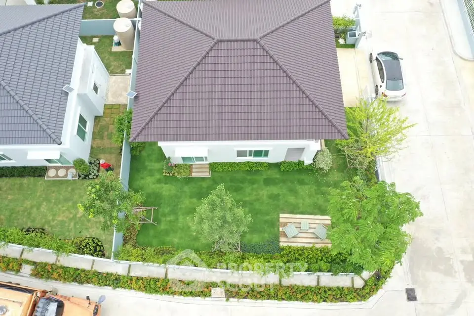 Aerial view of a modern house with landscaped garden and driveway.