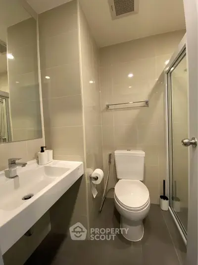 Modern bathroom with sleek fixtures and glass shower enclosure in a contemporary apartment.