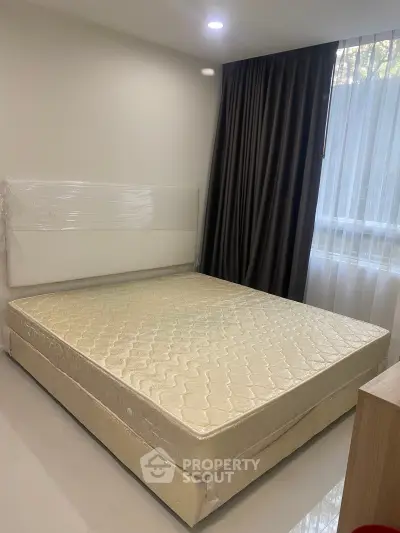 Spacious bedroom with large window and elegant curtains, featuring a comfortable bed and modern decor.