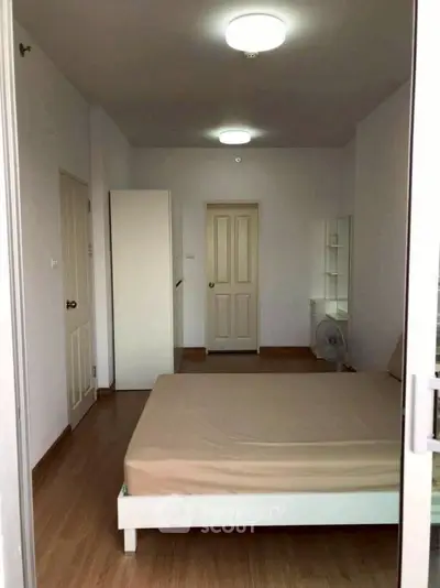 Spacious bedroom with minimalist design and ample natural light, featuring a comfortable bed and sleek wooden flooring.