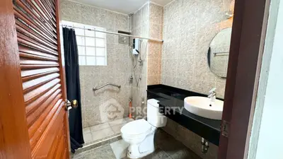 Modern bathroom with sleek fixtures and tiled walls, featuring a round mirror and black countertop.