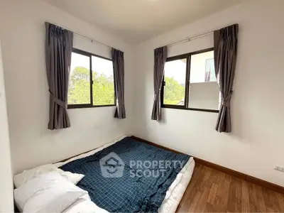 Cozy bedroom with large windows and wooden flooring