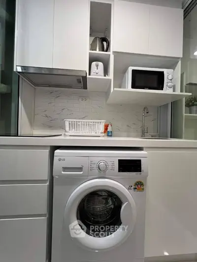 Modern kitchen with built-in washing machine and sleek white cabinetry