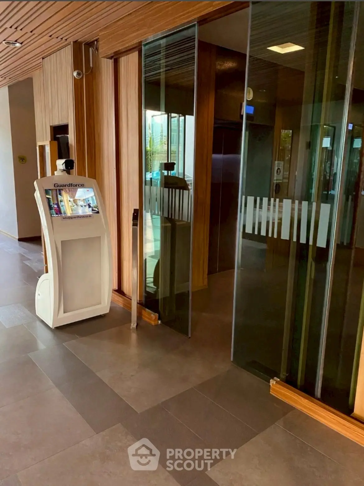 Modern building entrance with sleek elevator and security kiosk