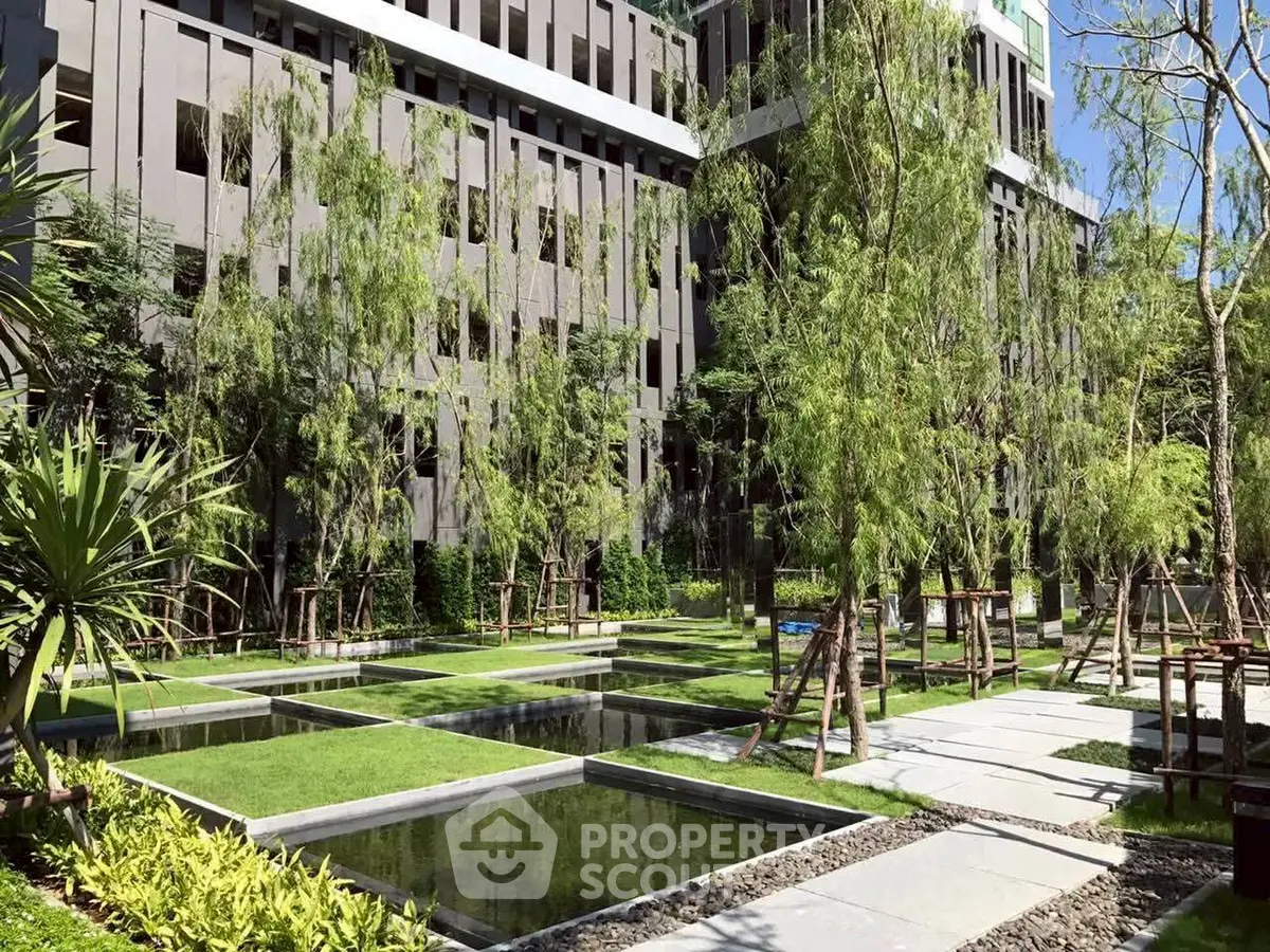 Modern building exterior with lush garden and water features, perfect for urban living.