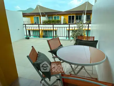 Spacious balcony with outdoor seating and scenic view in modern apartment complex.