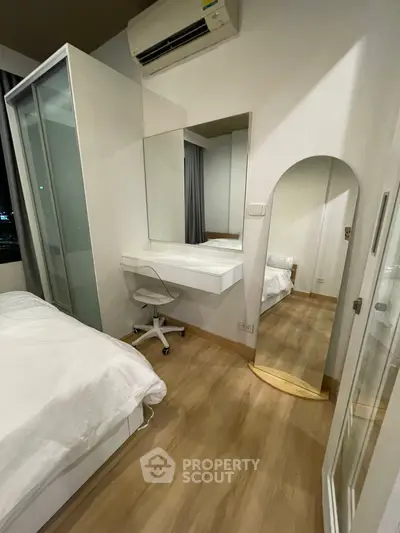 Modern bedroom with sleek design, featuring a large mirror and compact workspace.