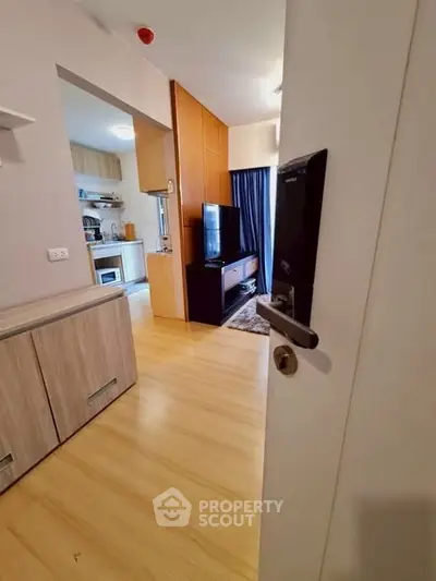 Modern apartment interior with open kitchen and cozy living area, featuring wooden flooring and stylish decor.
