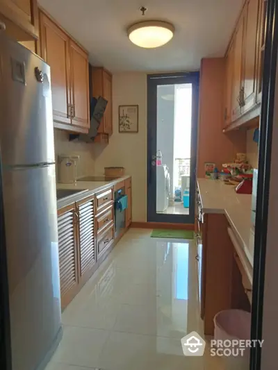 Spacious kitchen with modern appliances and wooden cabinetry, featuring a sleek design and ample natural light.