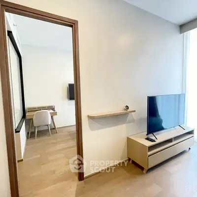 Modern living room with sleek TV stand and view into a stylish study area.