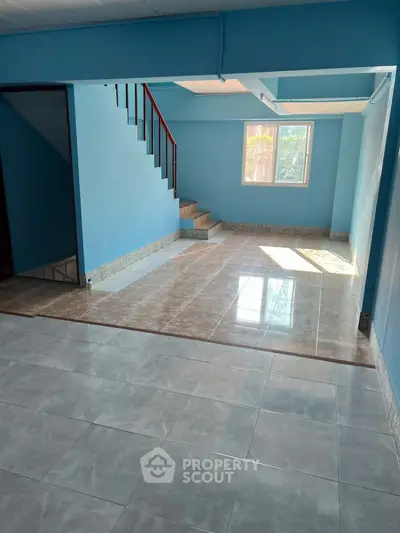 Spacious blue-walled interior with tiled flooring and staircase, perfect for modern living.