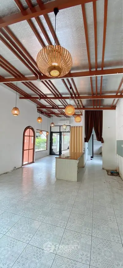 Spacious open-plan living area with modern lighting and large windows for natural light.