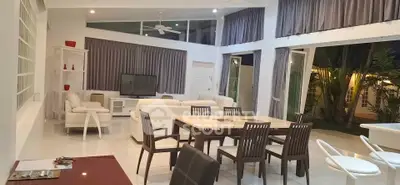 Spacious modern living room with high ceilings and large windows opening to a lush garden view.