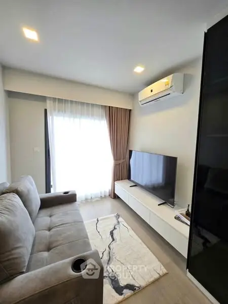 Modern living room with cozy sofa, TV, and air conditioning in a bright apartment.