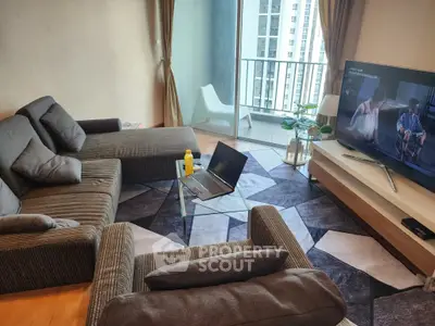 Modern living room with stylish sofa, geometric rug, and balcony view in a high-rise apartment.
