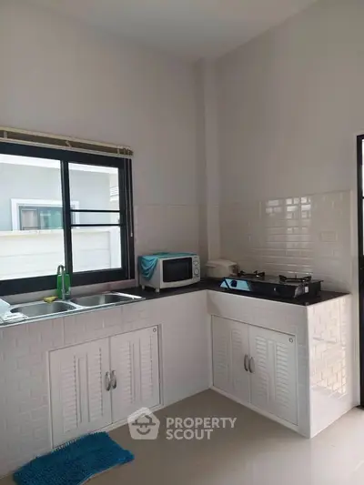 Modern kitchen with sleek countertops and gas stove, featuring a microwave and ample natural light.