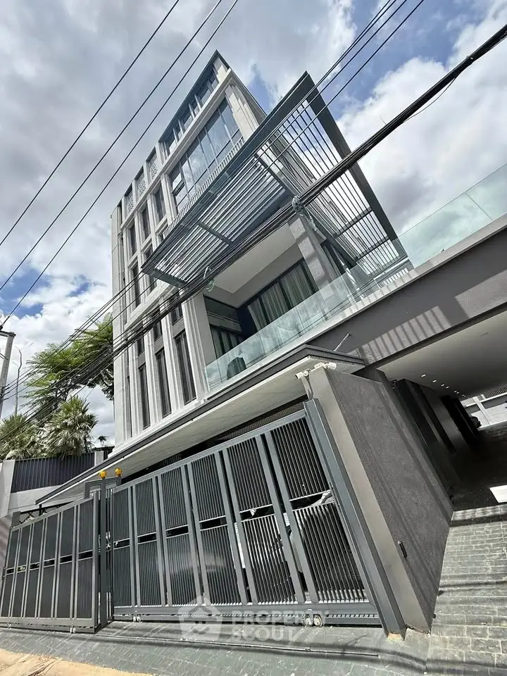 Modern architectural building with sleek design and glass facade under a cloudy sky.