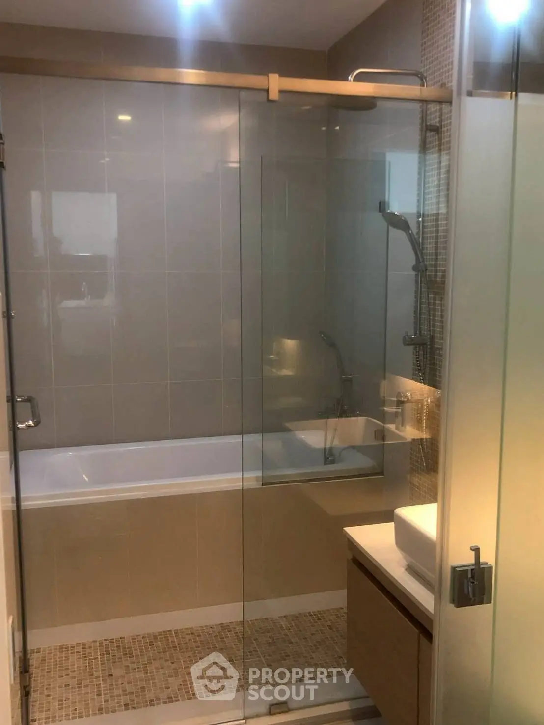 Modern bathroom with glass shower and bathtub in contemporary apartment.