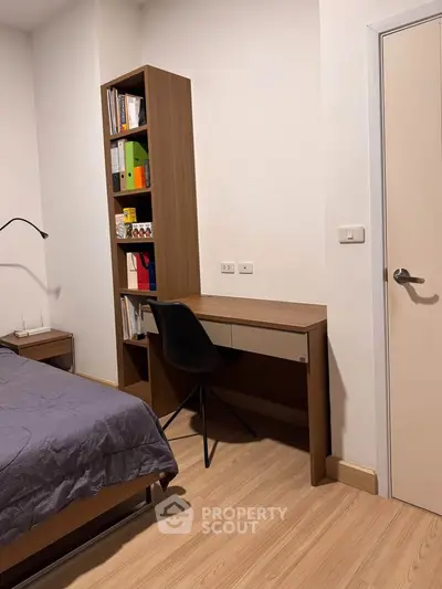 Modern bedroom with study area featuring a sleek desk and bookshelf, perfect for productivity.