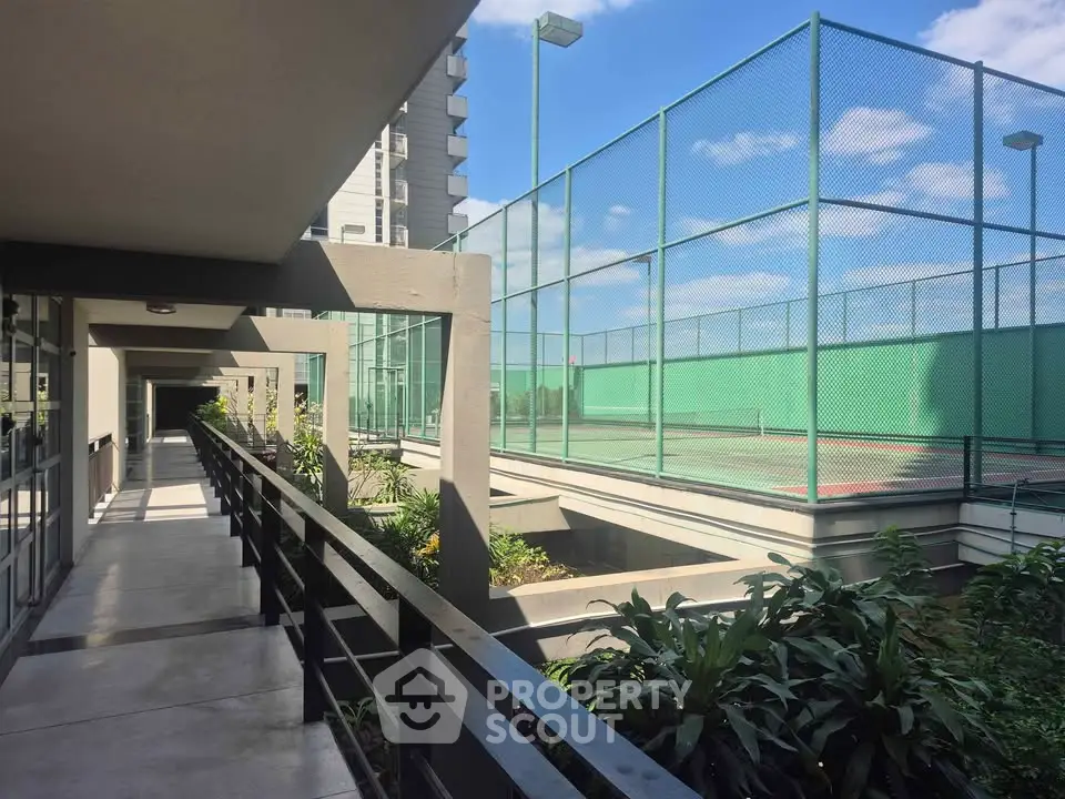 Modern apartment complex with tennis court and lush greenery, perfect for active lifestyle seekers.
