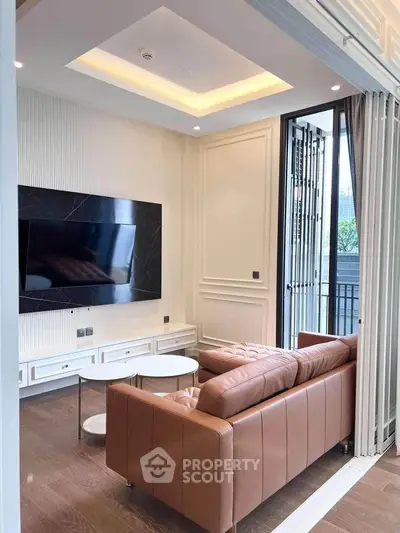 Luxurious living room with modern leather sofa and wall-mounted TV, opening to a spacious balcony.