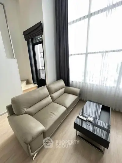 Modern living room with high ceilings and large windows, featuring a sleek sofa and stylish coffee table.