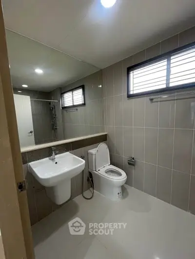 Modern bathroom with sleek fixtures and neutral tiles, featuring a spacious layout and contemporary design.