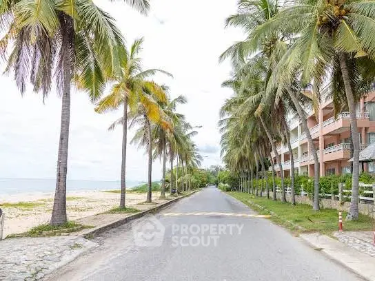 Beachfront property with palm-lined road and ocean view, ideal for tropical living.