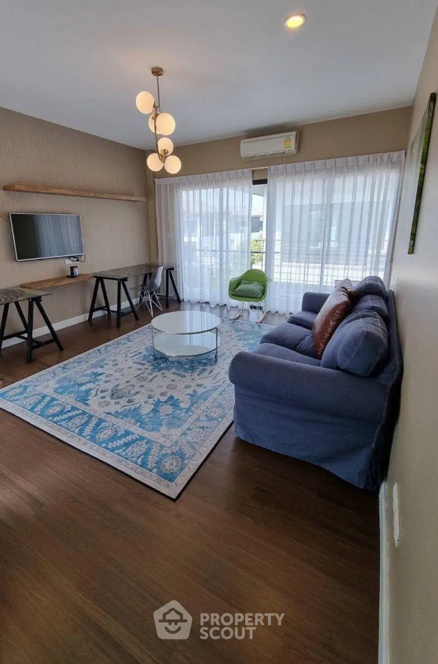 Stylish living room with modern decor, blue sofa, and large windows for natural light.