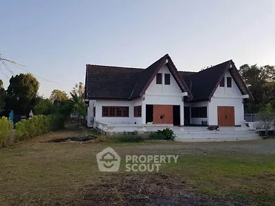 Charming countryside house with unique triangular roof design and spacious front yard.