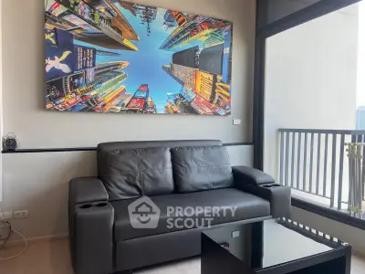 Modern living room with black leather sofa and vibrant cityscape artwork, featuring a sleek balcony view.