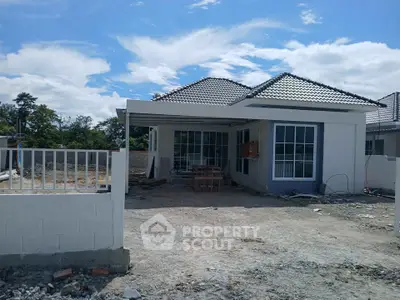 Charming single-story house with modern design and spacious front yard under clear blue sky.