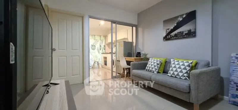 Modern living room with sleek gray sofa and open kitchen layout, perfect for urban living.