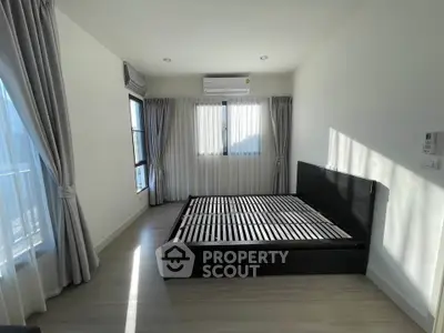 Spacious bedroom with modern bed frame and large windows for natural light