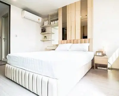 Modern bedroom with stylish decor and natural light, featuring a comfortable bed and elegant shelving.