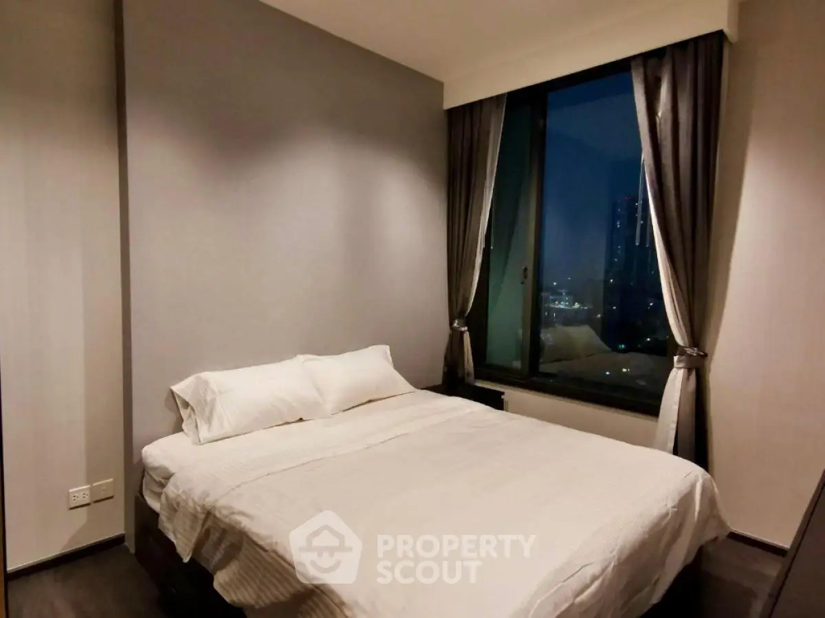 Cozy bedroom with city view and elegant curtains in modern apartment.