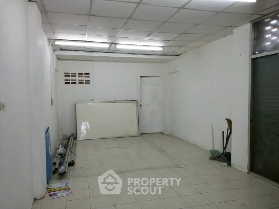 Spacious empty room with tiled floor and fluorescent lighting, ideal for customization.
